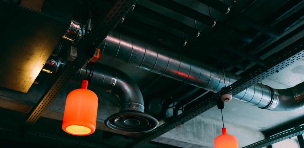 pexels photo 2464420 2464420 Low-angle view of a modern industrial ceiling featuring ducts and red lamps.