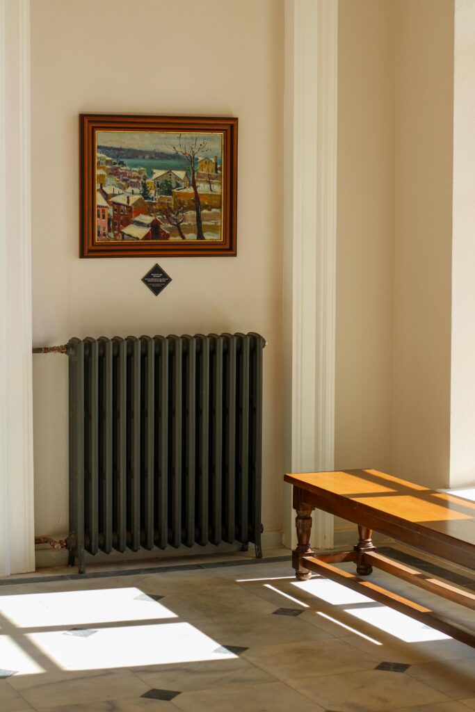 Bright interior with painting, radiator, and wooden furniture in natural light.